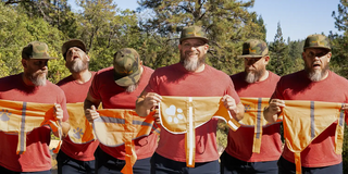 6 versions of the same man with beard and hat holding different reflective dog vests to compare