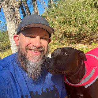 Shem & Luna - Man with beard smiling with curious black lab pit bull mix wearing pink SafetyPUP XD high visibility reflective dog vest