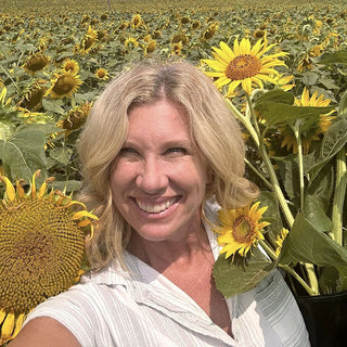 Stacy standing in sunflowers taking selfie